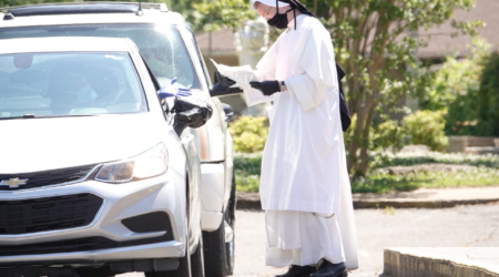 May 11, 2020- The Dominican Sisters of St. Cecilia say good by to school children as the school year wraps up outside St. Paul Church in Memphis, Tennessee on Monday. They used a drive through method to get their summer packets because of COVID 19 virus, students have been learning from home. The principal, Sister Mary Lawrence, O.P. was on hand to say greet the students. The sisters have administered the school since 1965. © Karen Pulfer Focht